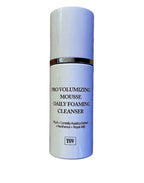 Skincare bottle labeled 'Pro Volumizing Mousse Daily Foaming Cleanser' on a dark background