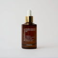 Brown serum bottle with gold cap and white dropper on a light gray background