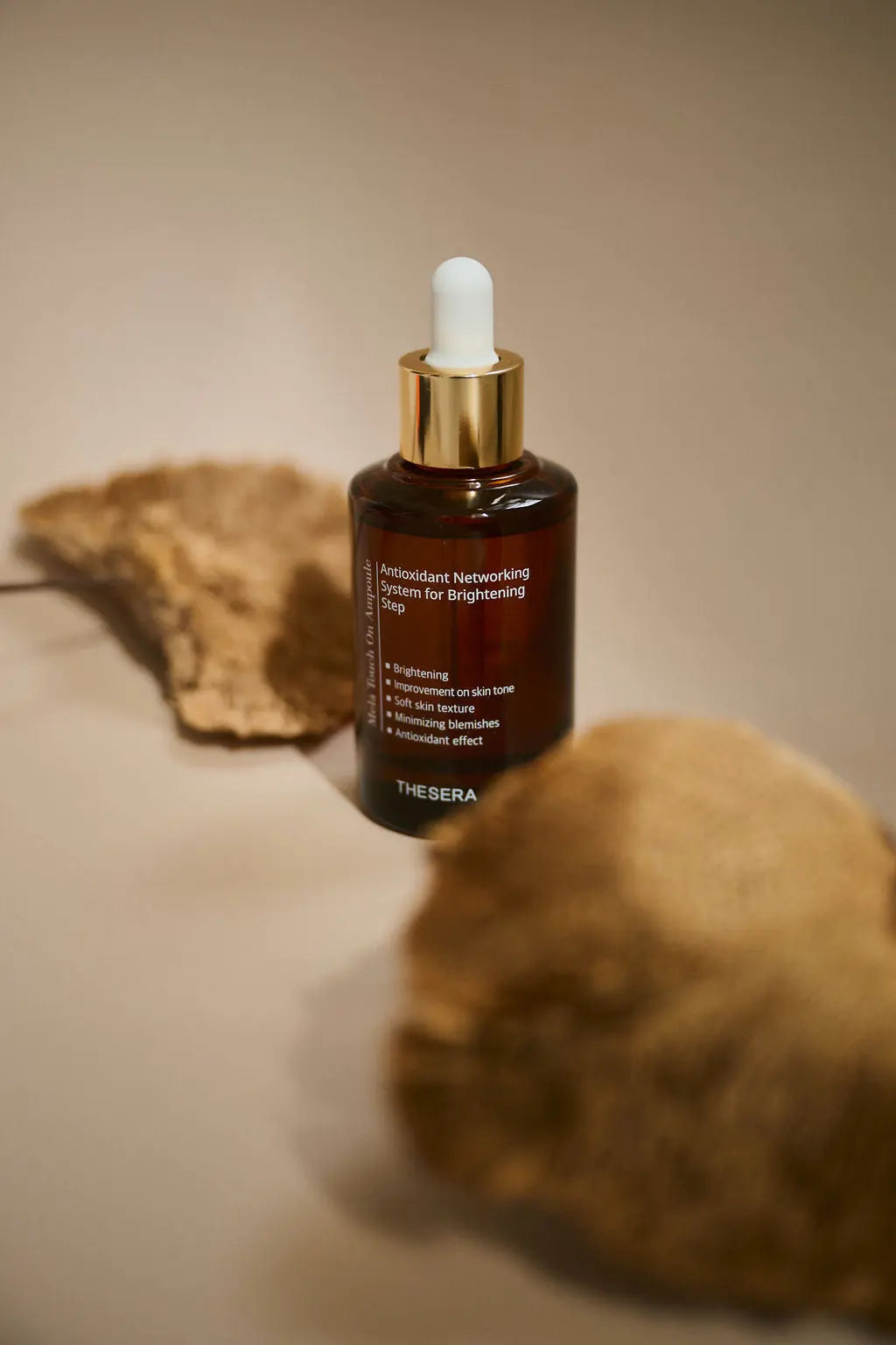 Brown serum bottle with dropper on a beige surface