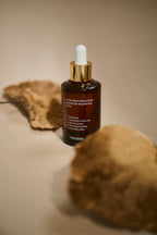Brown serum bottle with dropper on a beige surface